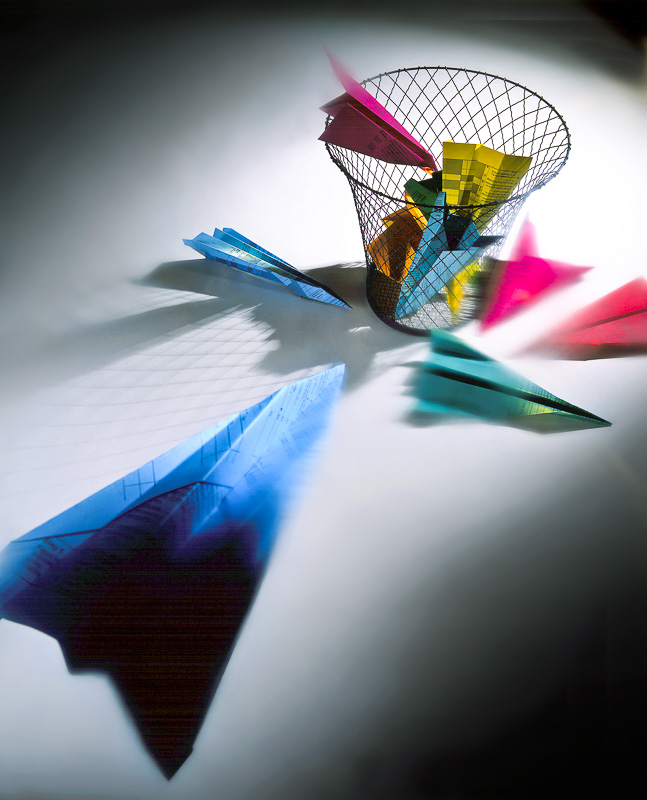 paper airplanes being throw at trash bin